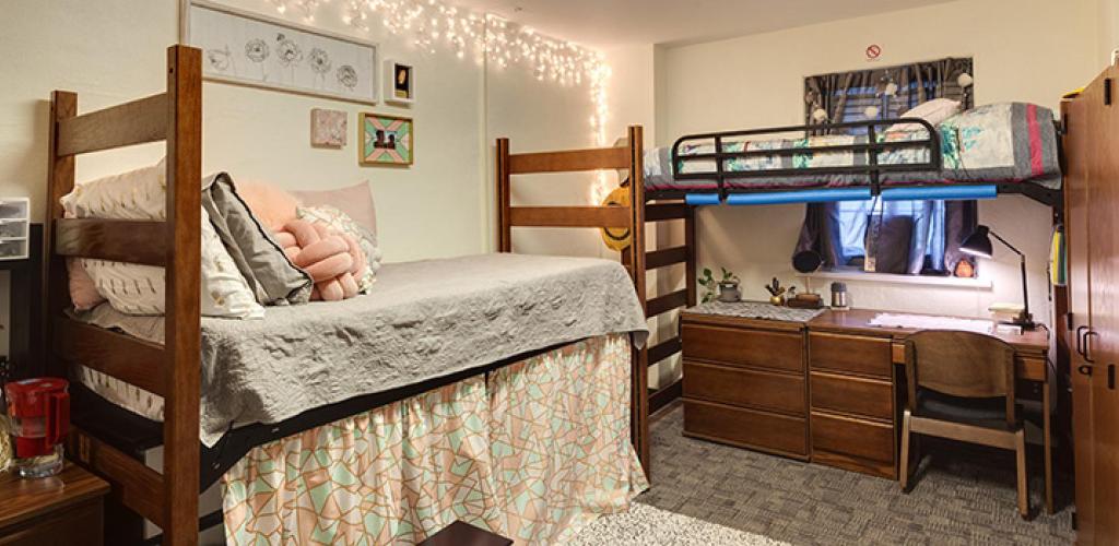 Bedroom. One bunk bed with a desk underneath another one risen enough to use as storage space.